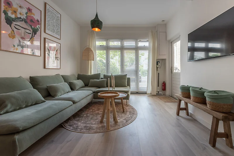 Modern woonkamer met bank, salontafel en grote ramen.