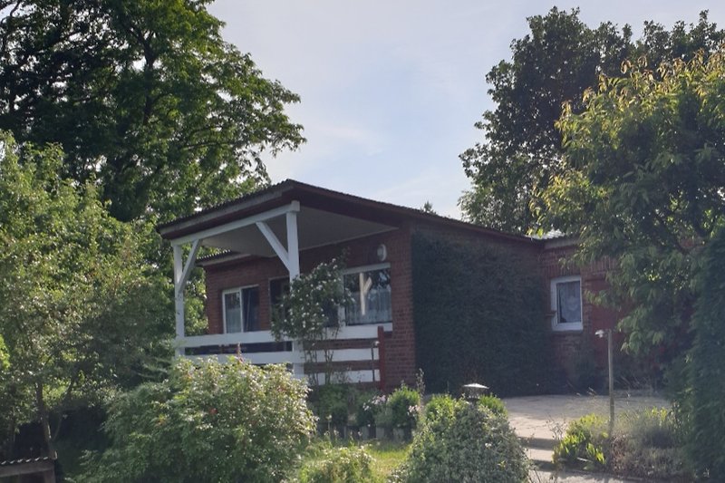 Charmantes Haus mit Holzfassade, Garten und blühenden Sträuchern.