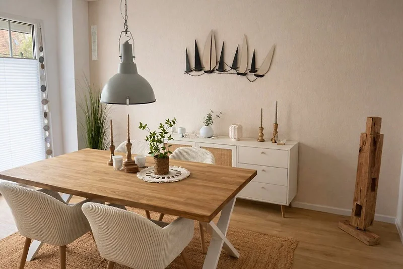 Esszimmertisch aus Holz, bequeme Stühle und dekorative Vase.