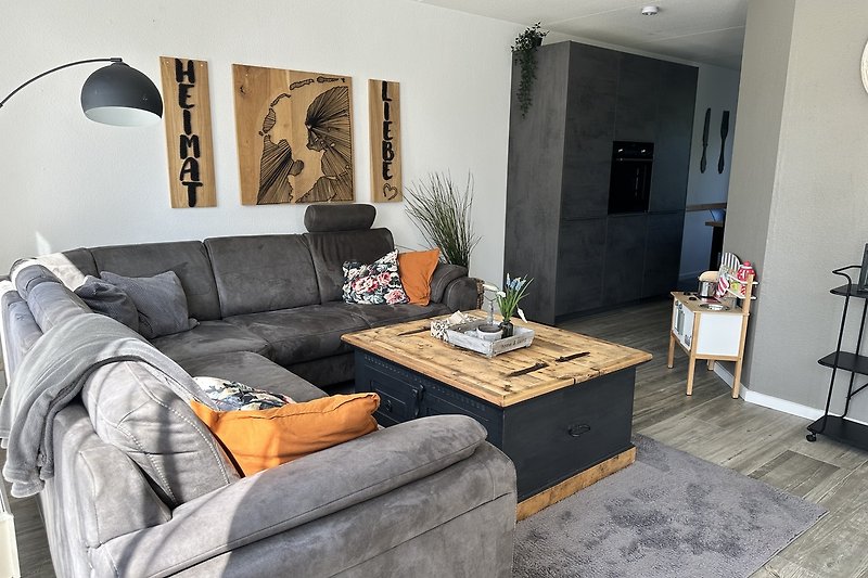 Offenes helles Wohnzimmer mit gemütlichem Sofa, Couchtisch und stilvollen Möbeln.