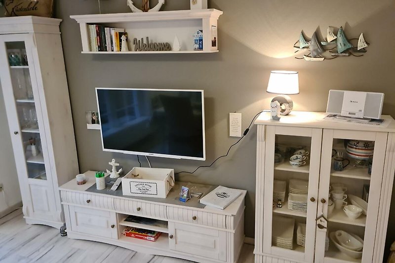 Wohnzimmer mit Holzschränken, Fernseher und Pflanzen.