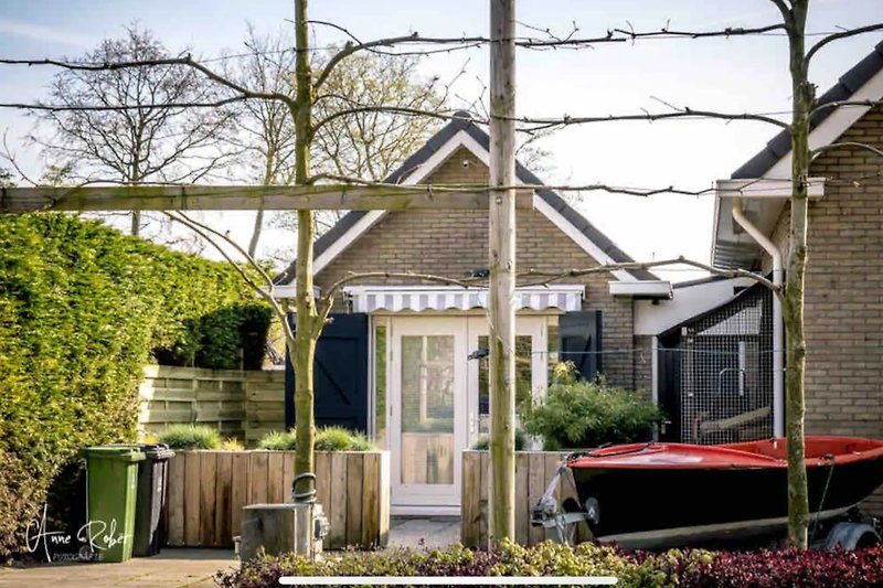 Gemütlicher Garten mit Holzveranda, Pflanzen und gepflegtem Rasen.