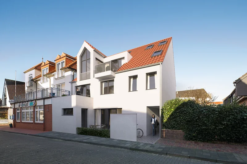 Charmant huis met een rood dak, grote ramen en groene planten.