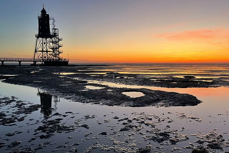 Sonnenuntergang am Meer mit Leuchtturm und weitem Horizont genießen.