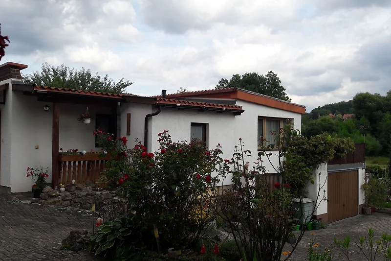 Charmantes Ferienhaus mit blühendem Garten, Bäumen und gepflegtem Rasen.
