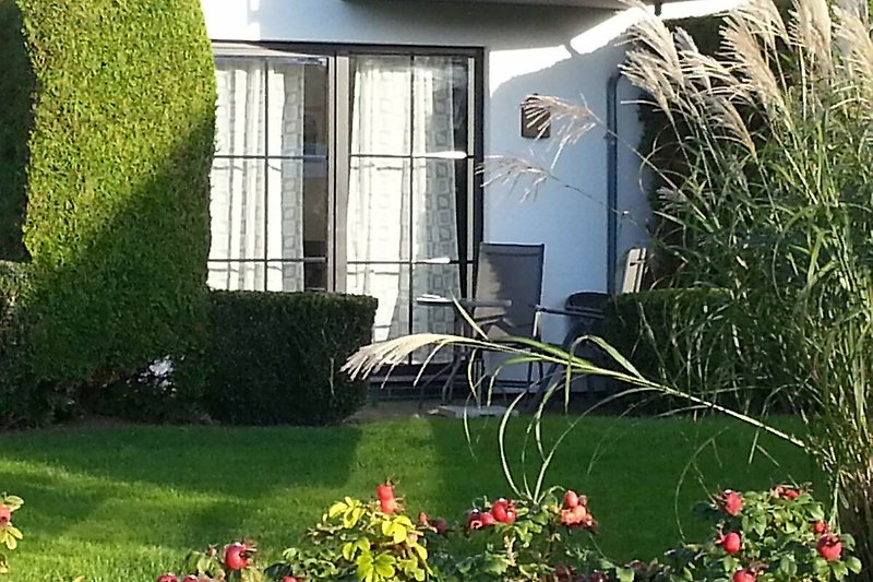 Garten mit Blumen, Rasen und gemütlicher Terrasse  mit Gartenmöbel