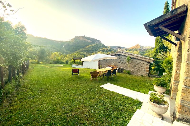 Bergblick mit Garten, Blumen, Bäumen und gemütlicher Sitzgelegenheit.