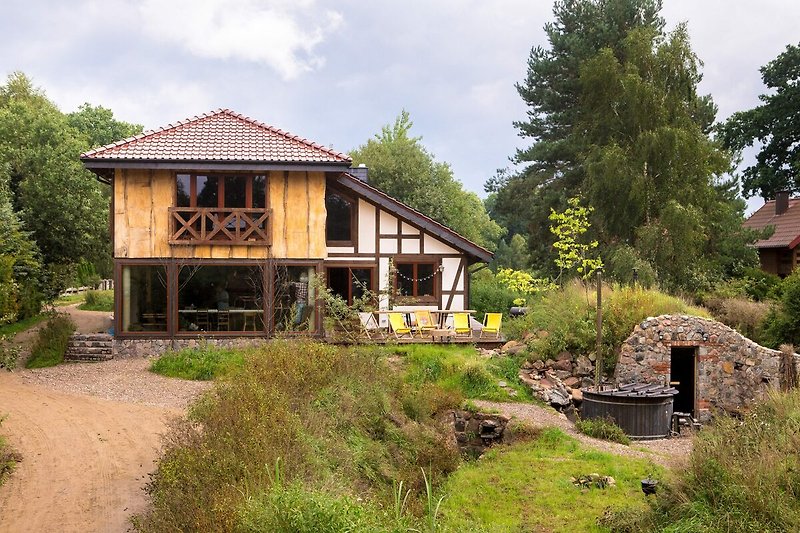 Charmantes Landhaus mit Garten, Bäumen und malerischem Himmel.