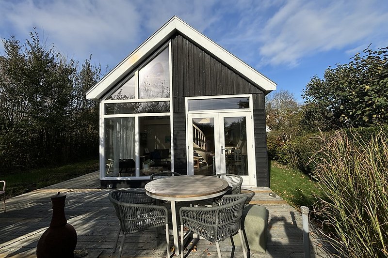 Holzhaus mit Garten, Terrasse und Pavillon im Grünen.