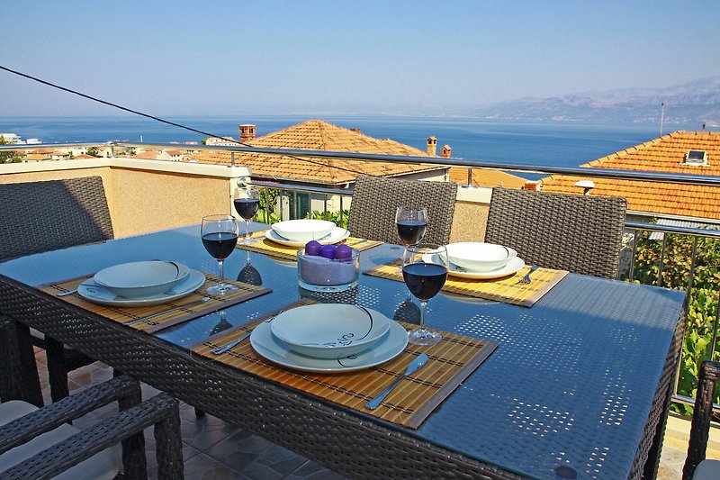 Ein Balkon mit Meerblick, schönen 
 Pflanzen und modernen Outdoor-Möbeln.