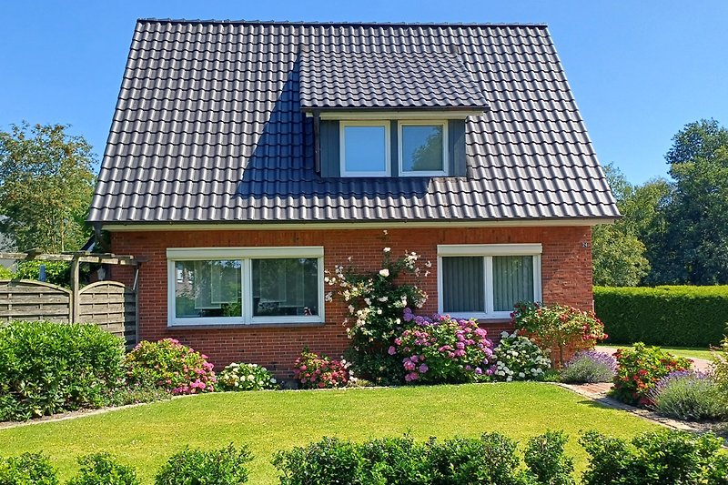 Charmantes Landhaus mit Garten und blühenden Sträuchern.