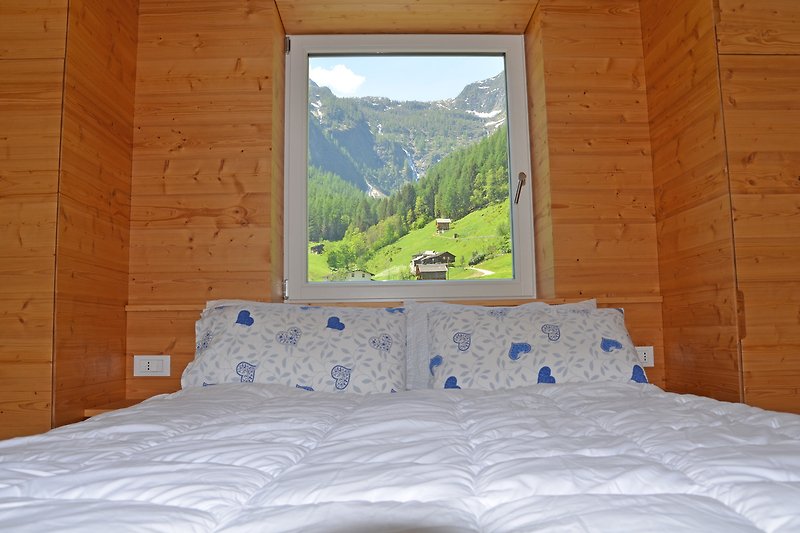 Schlafzimmer mit Bergblick, Holzbettrahmen und Fenster.