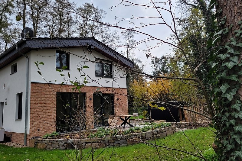 Rustikales Haus mit Holzfassade und grüner Umgebung.