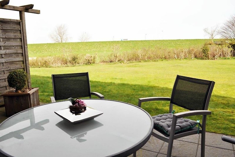 Gemütliche Terrasse mit angrenzender Liegewiese, Alumöbeln und unverbautem Weitblick.