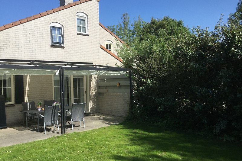 Charmantes Landhaus mit Garten, Bäumen und einladender Veranda.