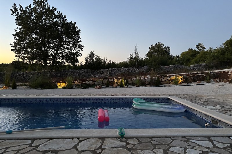 Pool mit Wasserspiel, Flagstone und gepflegter Landschaft.