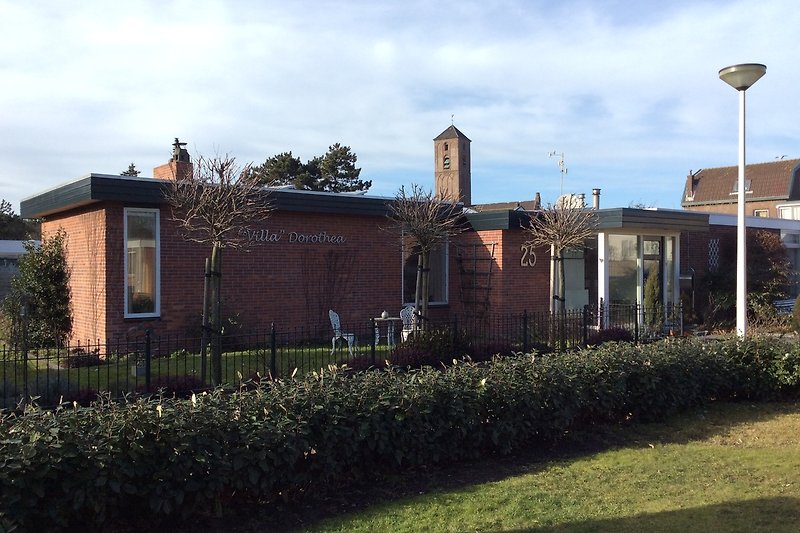 Elegantes Herrenhaus mit gepflegtem Garten und üppigen Bäumen.