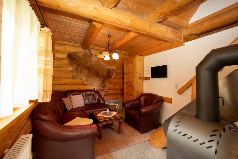 Gemütliches Wohnzimmer mit Holzmöbeln und Holzbalkendecke.