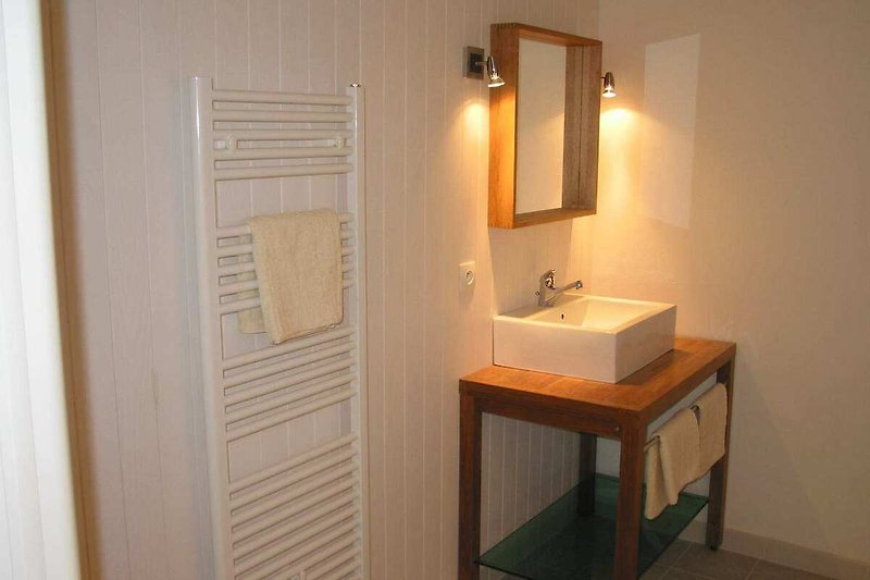 Badezimmer mit Spiegel, Waschbecken & Armatur.