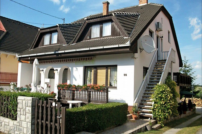 Historisches Haus mit Veranda, Schornstein und Sprossenfenstern.