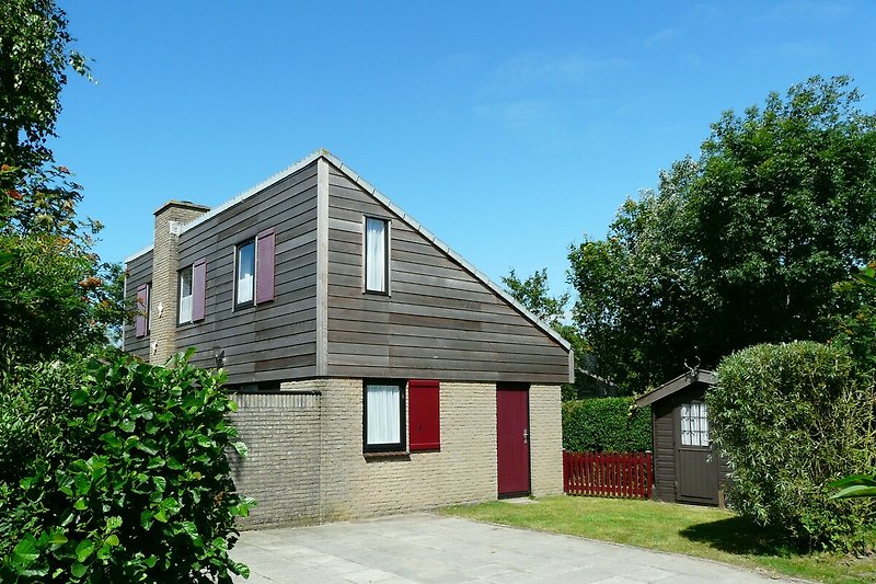 Einfamilienhaus mit Garten, Bäumen und gepflegtem Vorgarten.