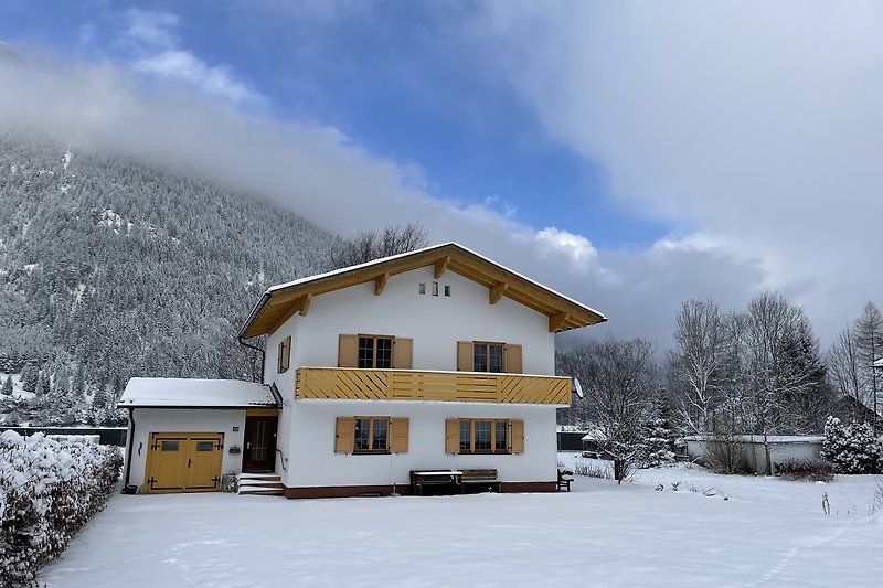 Winterliches Bergdorf mit verschneiten Hütten und Alpenblick.