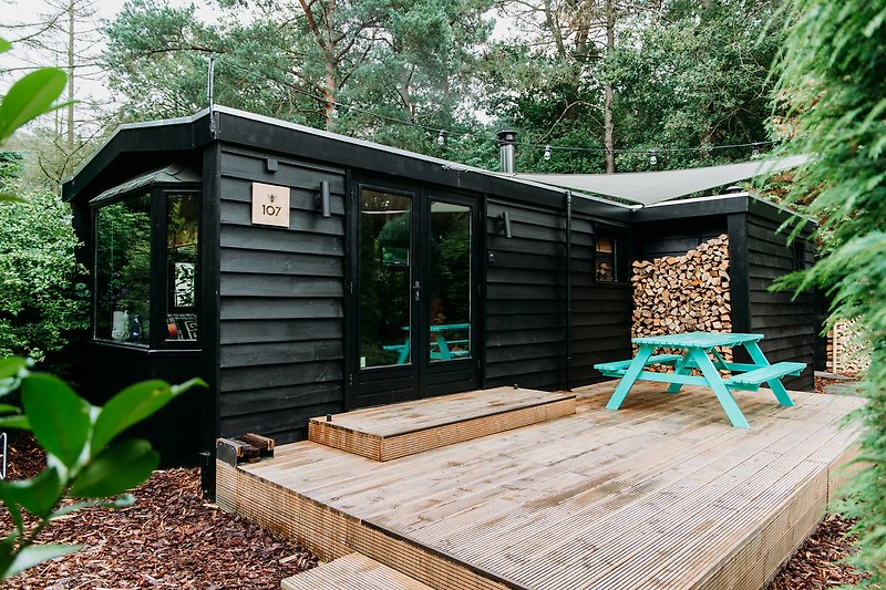 Holzterrasse mit Gartenmöbeln und Schuppen im Grünen.