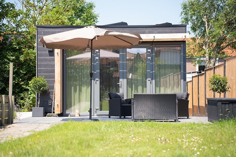 Gemütlicher Garten mit Pergola, Gartenmöbeln und blühenden Pflanzen.