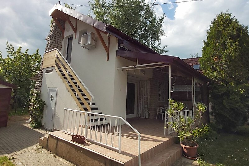 Haus mit Balkon, Auto und gepflegtem Vorgarten.