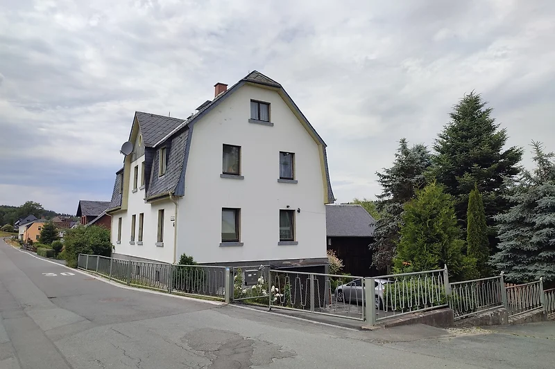Graues Haus mit Sprossenfenstern und Schornstein im Vorort.