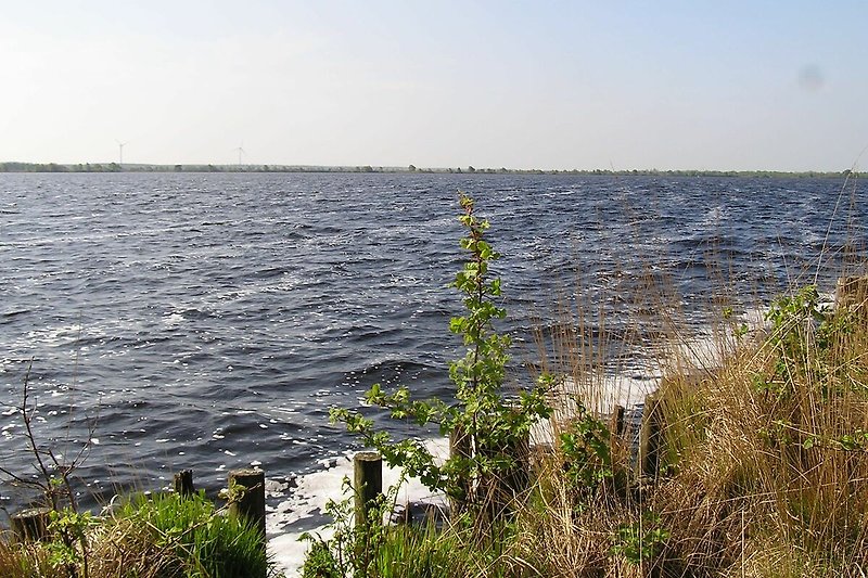 Blick auf das Meer mit Wellen und Küste im Hintergrund.