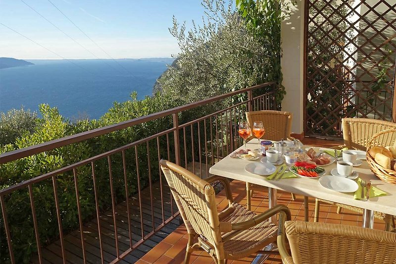 Balkon mit Meerblick, Holzmöbel und Pflanzen, ideal zum Entspannen.