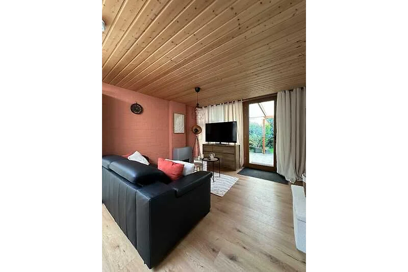 Gemütliches Wohnzimmer mit Holzdecke, Couch und Kaffeetisch.