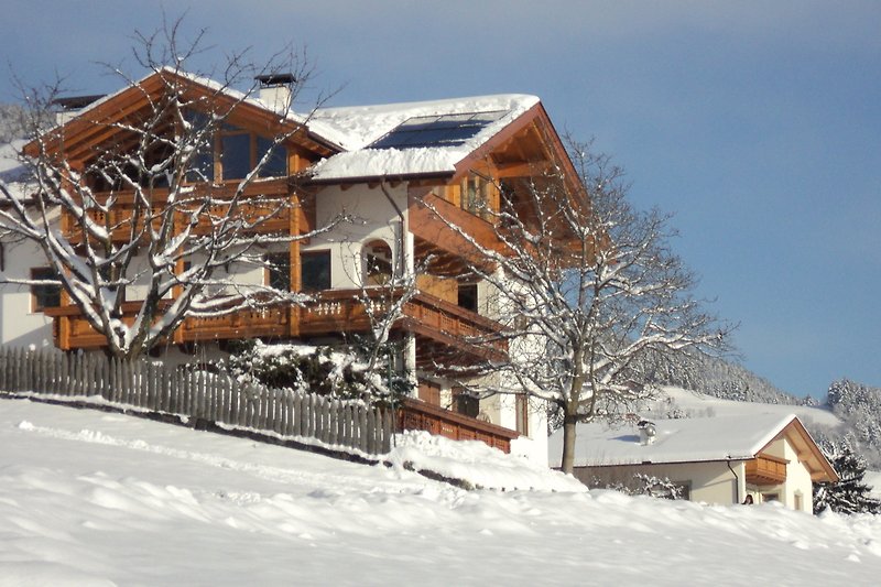 Gemütliches Chalet im verschneiten Bergdorf mit Blick auf die Alpen.