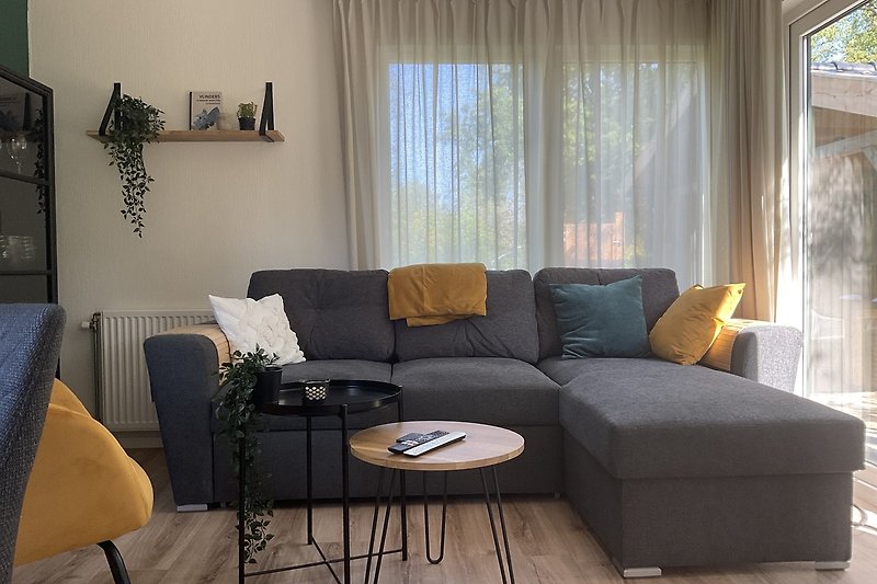 Wohnzimmer mit Couch, Kissen, Couchtisch und Zimmerpflanze.