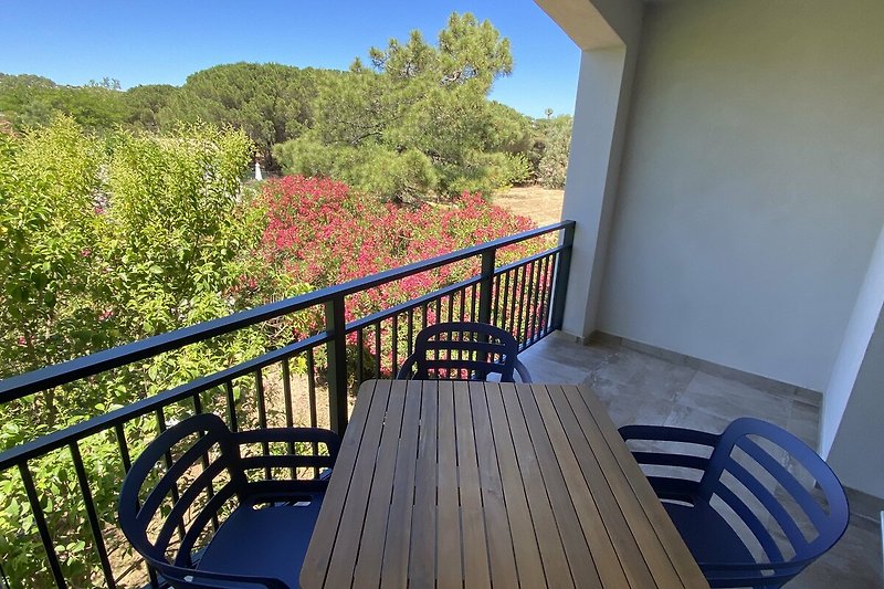 Geräumiger Balkon mit Holzmöbeln und schattigem Essbereich.