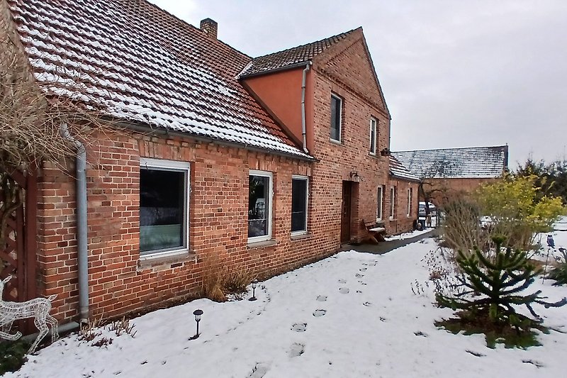 Historisches Haus mit Ziegelmauerwerk, Schornstein und verschneitem Dach.