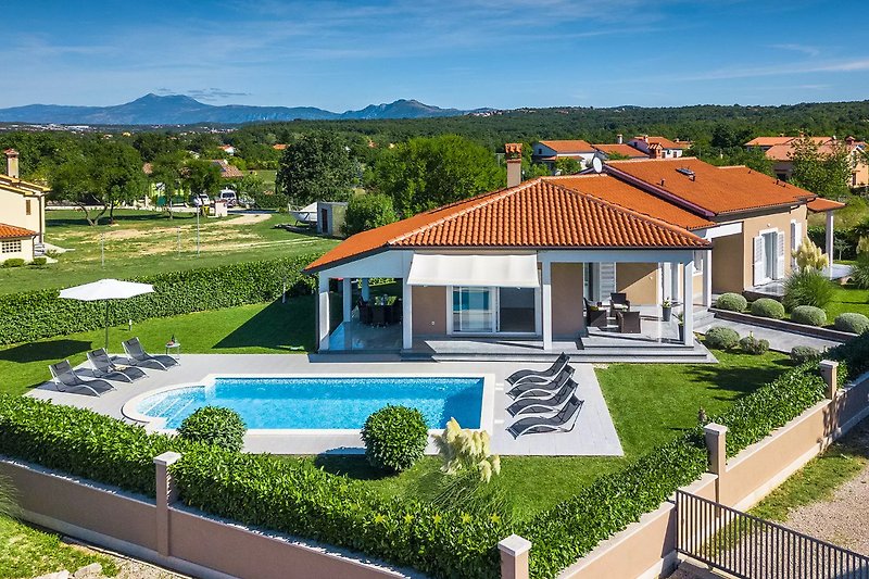 Villa mit Pool, umgeben von gepflegtem Garten und Veranda.