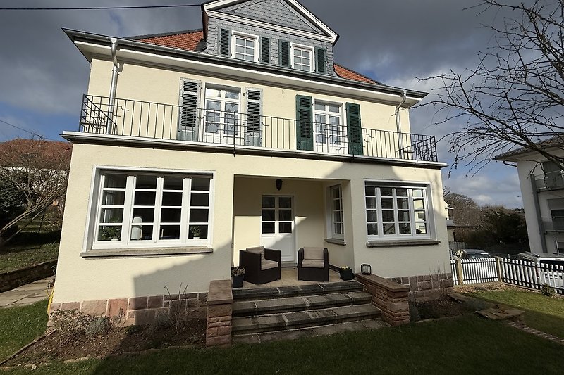 Große Veranda mit Balkon und gepflegtem Vorgarten.