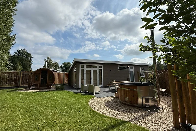 Großer Garten mit Rasen, Gartenhäusern und Holzschuppen.
