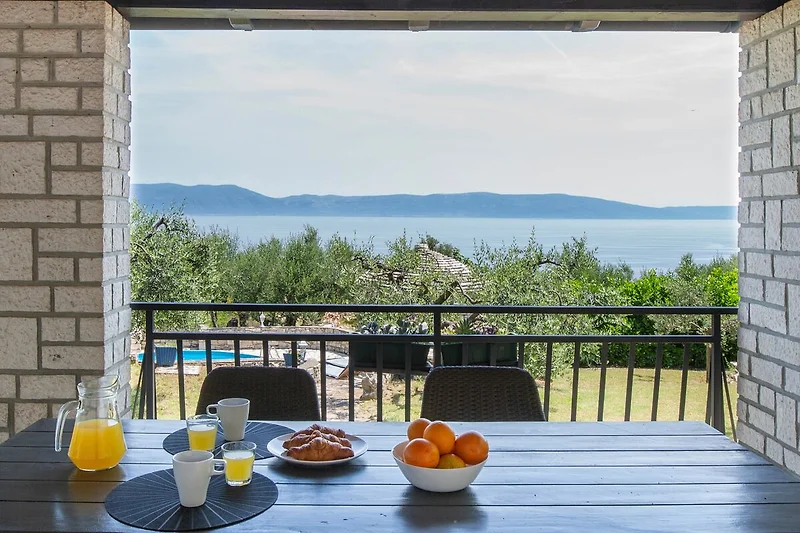 Große Veranda mit Möbeln, Balkon, Tisch und Stühlen im Freien.