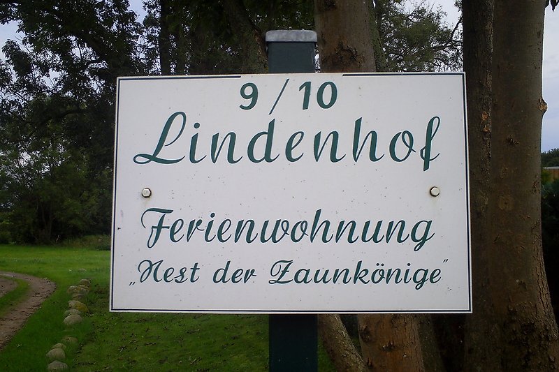 Straßenschild und Adresse inmitten grüner Natur und Bäume.