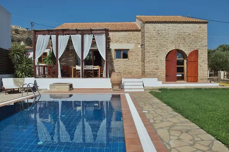 Villa mit Pool, Sonnenliegen, Sonnenschirm und Gartenmöbeln.