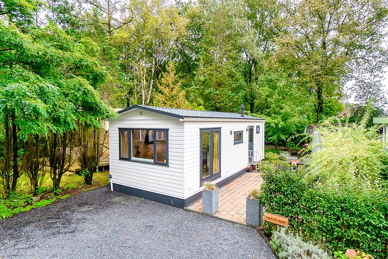 Cottage mit Gartenhäuschen und Mobilheim im grünen Umfeld.