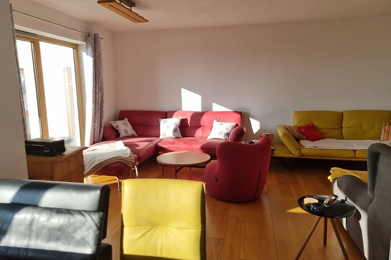 Wohnzimmer mit komfortablem Sofa, Sessel und Holztisch.
