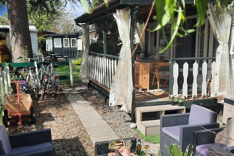 Holzveranda mit Gartenmöbeln und schattigem Bereich.