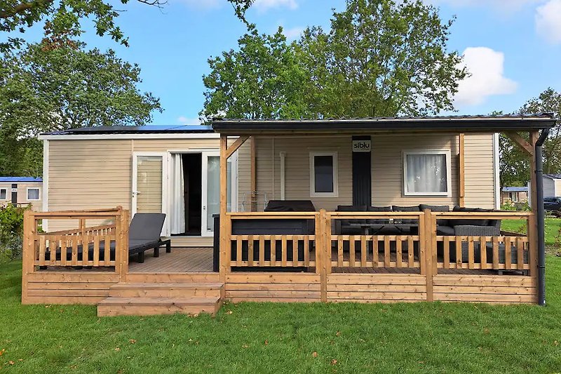 Mobilheim mit Holzveranda und Gartenhäuschen.