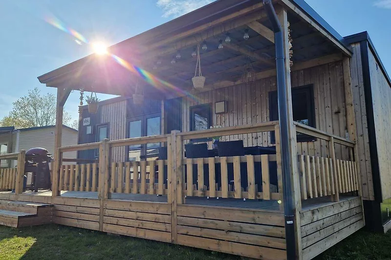 Holzveranda mit Zaun und Gartenhaus im Schatten.