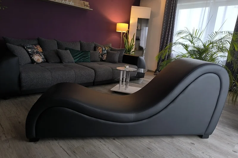 Wohnzimmer mit Ledersofa, echten Pflanzen, Vitrinen, Kuscheldecke, Kissen und Chaiselongue.