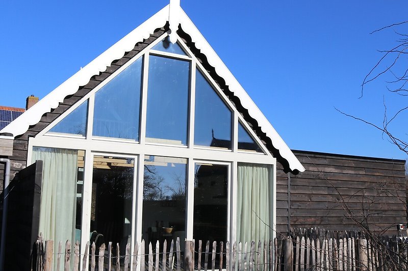 Holzhaus mit Satteldach und Gartenansicht.